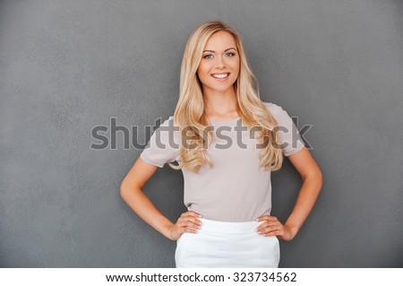 [[stock_photo]]: Smiling Young Woman With Hand On Her Hip Against A White Background