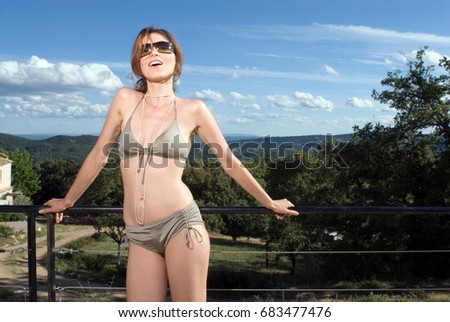 Foto stock: Smiling Woman Wearing Bikini Standing On Balcony With Pool On Background