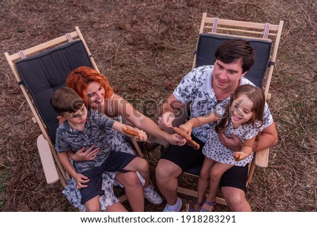 Foto d'archivio: The Boy Is Sitting At The Camp Fire And Eating A Fried Sausage