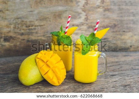 Stock photo: Juicy Smoothie From Mango In Two Glass Mason Jars With Striped Red Straw On Old Wooden Background H