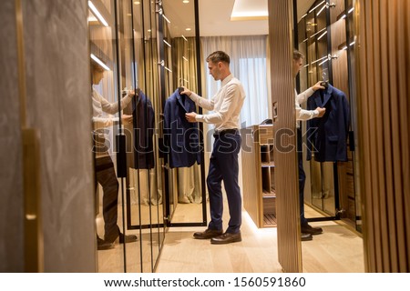 Stock photo: Young Man Choosing Clothes From Wardrobe In The Hall Of Contemp