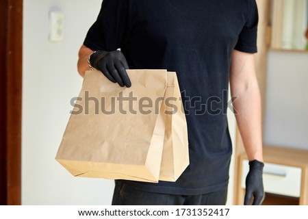 Stock foto: Courier Man In Black Delivery Box With Food Contactless Delivery