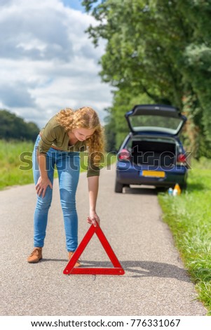 Stockfoto: Dutch Woman Placing Warning Triangle On Rural Road