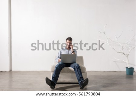 Young Freelancer Sitting In Armchair In Agency Working On Laptop Foto stock © Kzenon
