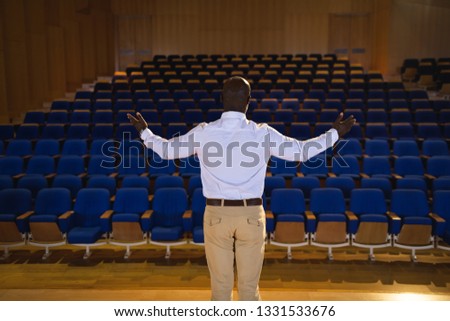 [[stock_photo]]: Rear View Of Old African American Businessman With Arm Stretched Out Standing In A Auditorium