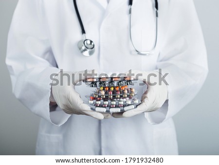 Foto stock: Medical Doctor Wearing Clear Latex Gloves Holding Stack Of Different Pills Antibiotics And Virus Tr