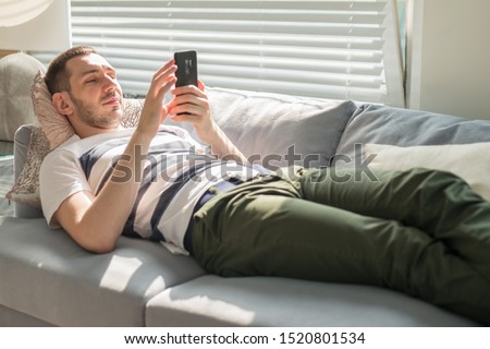 [[stock_photo]]: Handsome Young Man Relaxing On Sofa And Calling With His Smart P