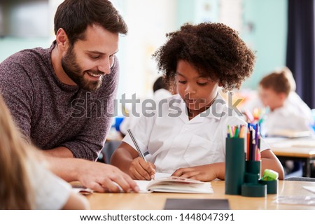 Foto stock: Male Primary School Pupil And Teacher Working At Desk In Classro