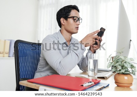 Foto d'archivio: Portrait Of A Pensive Asian Man Sitting In Office With His Colleagues In Background