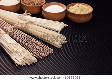 Stock photo: Assortmen Of Bundles Raw Noodles With Ingredient In Wooden Bowls On Black Striped Mat Background Wit