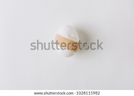 Stockfoto: Broken White Egg With Medical Plaster Laying On White Background