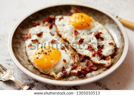 Foto d'archivio: Two Fresh Fried Eggs With Crunchy Crisp Bacon Served On Rustic P