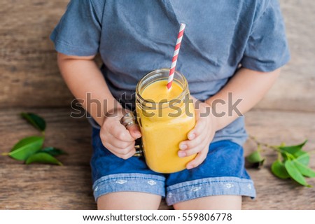 Stock photo: Boy Drinking Juicy Smoothie From Mango In Glass Mason Jar With Striped Red Straw On Old Wooden Backg