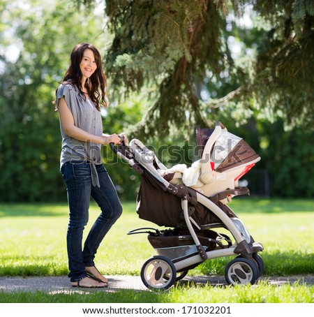 Stock photo: Portrait Of Beautiful Young Woman Pushing Baby Carriage In The Park