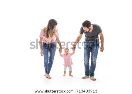 ストックフォト: Couple Of Young Parents Helping Their Baby To Make First Steps On Floor In Their Home