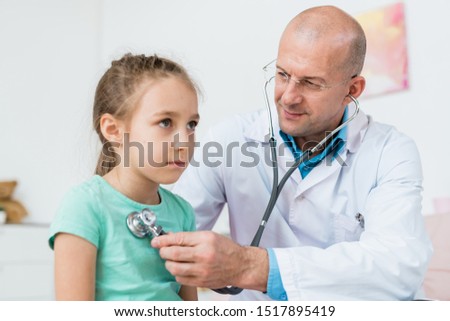 Zdjęcia stock: Young Bald Doctor Using Stethoscope For Treatment Of Sick Little Girl