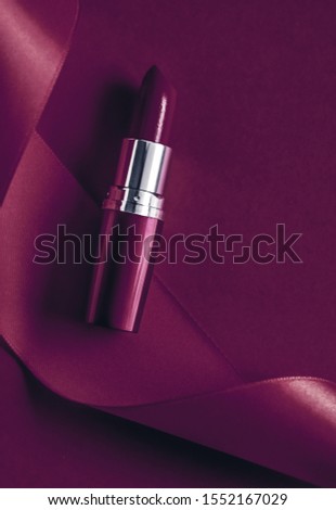 Foto d'archivio: Luxury Lipstick And Silk Ribbon On Plum Holiday Background Make