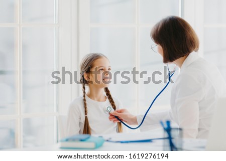 Stok fotoğraf: Lovely Small Girl Listens Consult Of Professional Experienced Doctor Who Listens Her Lungs With Stet