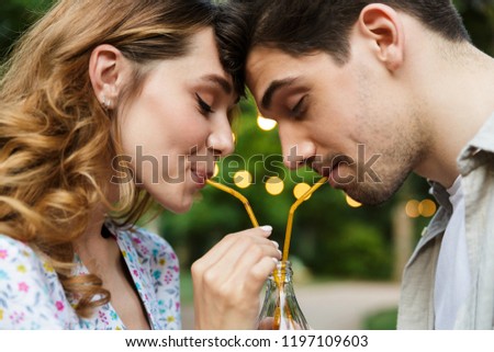 Imagine de stoc: Young Loving Couple Outdoors In Park Having Fun Drinking Soda Together