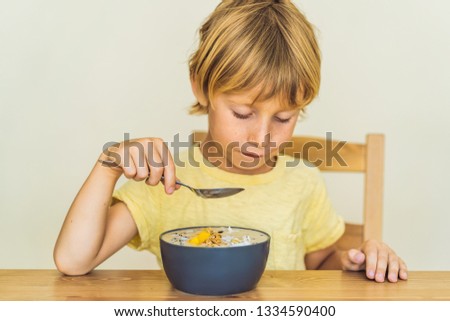 [[stock_photo]]: Happy Boy Sitting And Eating A Fresh Smoothie Bowl With Mango D