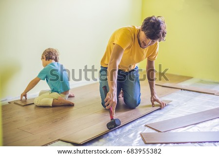 ストックフォト: Father And Son Installing New Wooden Laminate Flooring Infrared Floor Heating System Under Laminate