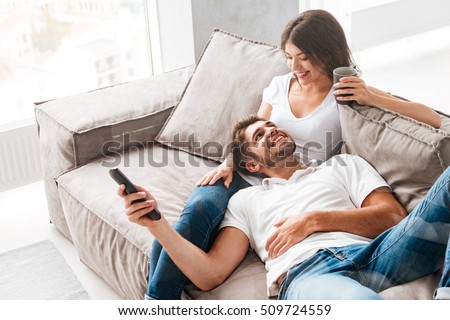 Foto stock: Loving Young Couple Sitting On The Couch At Home With Cellphone And Laotop