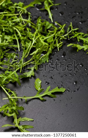 Foto stock: Green Fresh Rucola Or Arugula Leaves Closeup On Black Wet Backgr