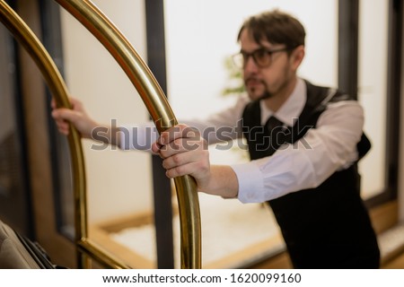 Foto stock: Hand Of Porter Holding By Handles While Pushing Cart And Picking Up Luggage