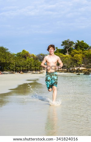 Foto stock: Young Boy With Red Hair In Swimsuit Is Running Along The Beautif
