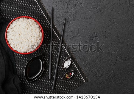 [[stock_photo]]: Black Bowl With Boiled Organic Basmati Jasmine Rice With Black Chopsticks And Sweet Soy Sauce On Bam