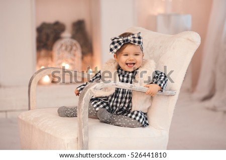 ストックフォト: Smiling Baby Girl Under 1 Year Old Wearing Stylish Clothes Sitting In Vintage Chair Over White Firep