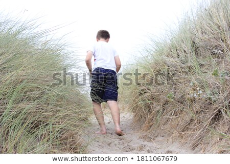 Stock fotó: Man Walking Through Grass In Sand Dune