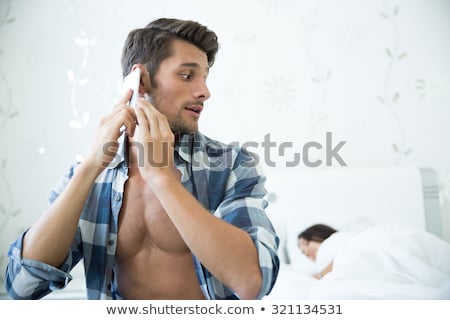 Foto stock: Man Talking Secretly On Cellphone While His Wife Sleeping