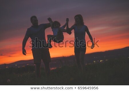 Stok fotoğraf: Mother And Father Swinging Son Up In The Air At Sunset