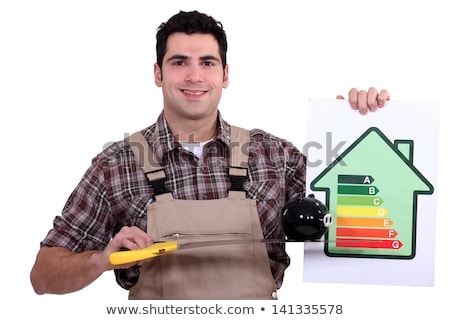 Foto d'archivio: Craftsman Holding A Pig Bank And An Energy Consumption Label