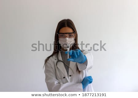 ストックフォト: Young Woman Doctor With Stethoscope Holding Syringe In White Uniform On White Background