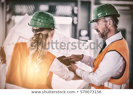 Stockfoto: Architects Discussing With Blueprint In Office Corridor