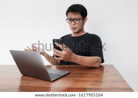 Stock photo: Wow Face Of Young Asian Man Shocked What He See In Laptop When Calling On Phone Indonesian Man Wear