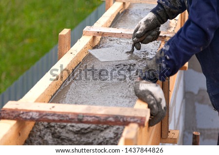 Foto stock: Construction Worker Using Trowel On Wet Cement Forming Coping Ar