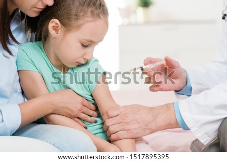 Stock fotó: Cute Little Girl Is Scared Of Injection While Looking At Syringe In Doctor Hand