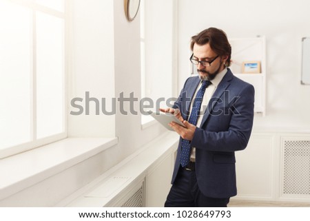 Foto d'archivio: Serious Entrepreneur In Formalwear Holding Touchpad While Surfing In The Net