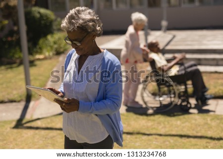 Stockfoto: Front View Of Senior Woman Using Digital Tablet In Garden On A Sunny Day