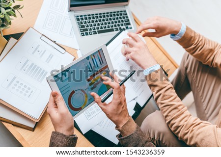 [[stock_photo]]: Two Young Analysts Sitting By Workplace While Working With Data And Documents