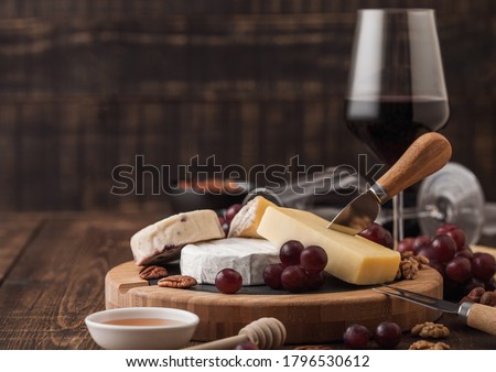 Foto stock: Glass Of Red Wine With Selection Of Various Cheese On The Board And Grapes On Wooden Background Blu