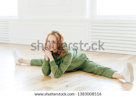 Stok fotoğraf: Amazing Flexibility Satisfied European Woman With Ginger Hair Makeup Does Splits While Sits On Wo