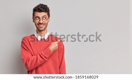 Stock photo: Sideways Shot Of Handsome Man With Stubble Looks With Puzzlement Aside Keeps Hand On Chin Wears Sp