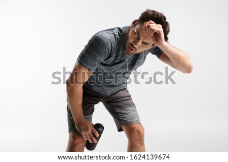 Stock photo: Image Of Young Tired Man Using Earphones And Holding Water Bottle