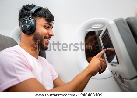 Foto stock: Passenger In Airplane Using Headphones Man In Plane Cabin Listening To Music On Headphones