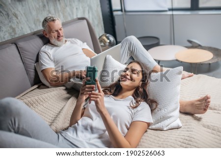 Zdjęcia stock: Top View Of Pleased Woman With Dark Long Hair Focused Into Book Reads Something Exciting Enjoys C