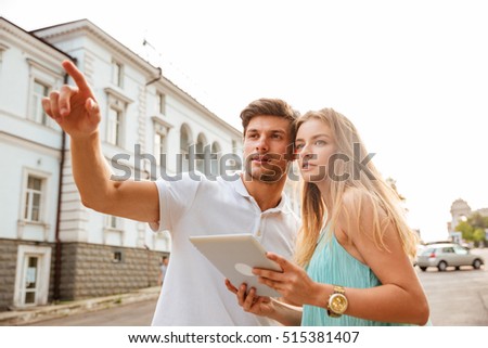 Foto d'archivio: Couple Holding Tablet While He Points Finger Away At Something